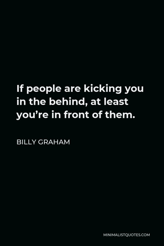 Billy Graham Quote - If people are kicking you in the behind, at least you’re in front of them.